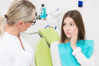 Girl having dental pain talking to a dentist at the dental clinic