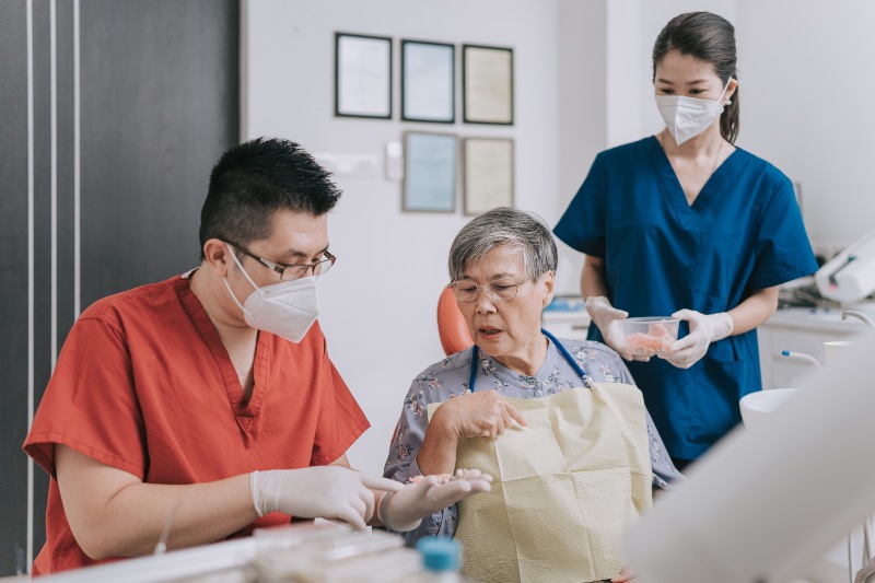 A dentist explaining dental bridges to a patient with an assistant in Westlake, OH